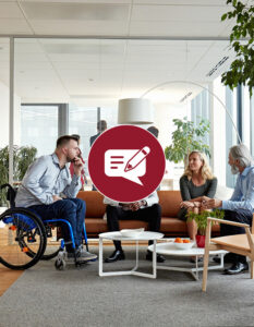 Four people sitting in a waiting area on a couch and speaking together in a group. One person is sitting in a wheelchair.